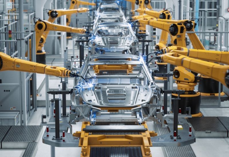 Automatizovaná linka v moderní automobilce s robotickými rameny, která svařují karoserie aut ve výrobním procesu.